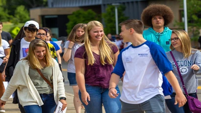 group of students walking behind a orientation leader outside